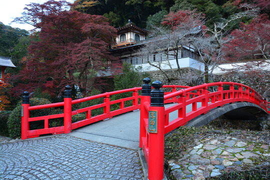 Red wooden bridge over river leading to Minooyama Ryuanji temple at Minoo Park in Osaka, Japan