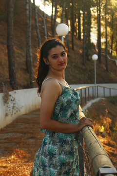 Side view of young woman standing beside wooden fence outdoor