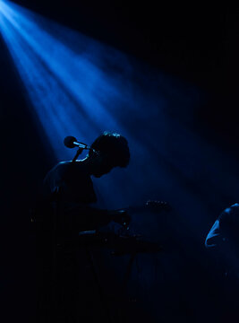 Silhouette of a man playing guitar on stage