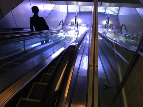 Silhouette of a man standing on escalator
