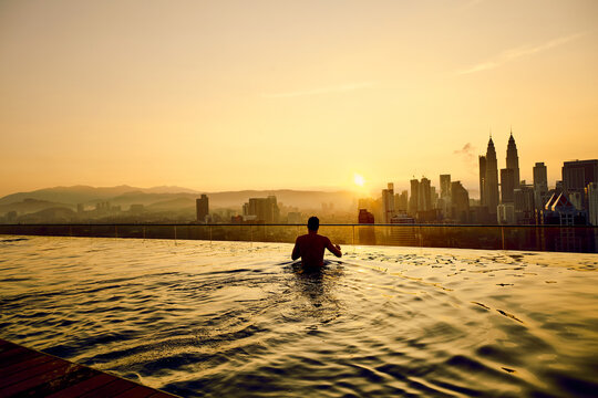 Silhouette of man in swimming pool, Man In Infinity Pool on top of building at kuala lumpur hotel
