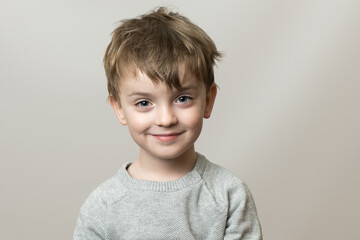 child of European appearance on a gray background with a smile. horizontal portrait. emotions