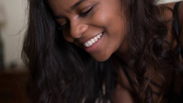 Smiling woman with black hair looking down