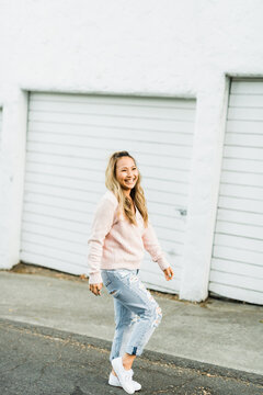 Smiling woman wearing pink sweater walking on road