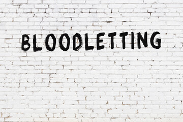 White wall with black paint inscription bloodletting on it