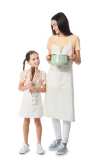 Young mother and daughter with kitchen utensils on white background