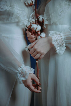 Two women in vintage wedding dresses holding a bouquet of flowers