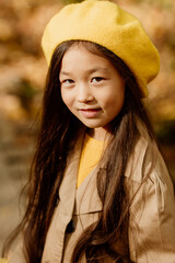 a little brunette Asian girl in autumn clothes walks in the autumn forest near a stream. High quality photo