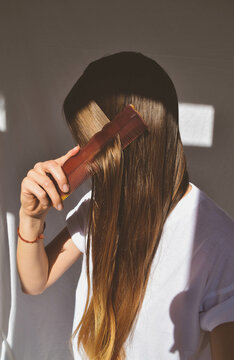 Woman brushing her hair indoors during daytime
