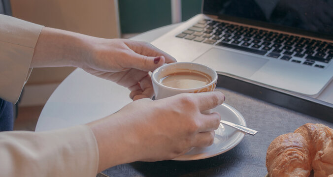 Woman holding mug next to her laptop