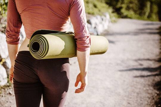 Woman holding yoga mat walking in nature