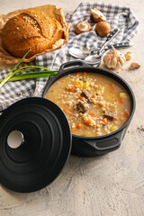 Cooking pot with tasty beef barley soup on grunge background