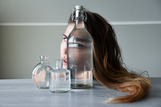 Woman showing her head behind three bottles of water on a gray table