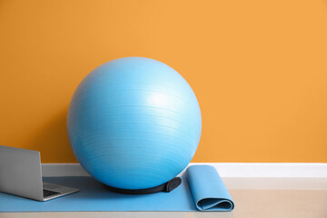 Set of sports equipment and laptop on floor near color wall