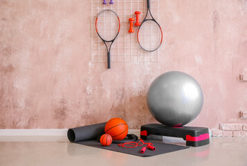 Different sports equipment  near color wall