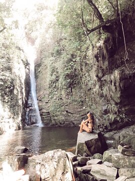 Woman sitting on rock near waterfalls
