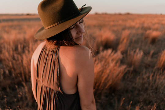 Woman wearing brown top and hat standing in field