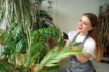 Obraz premium An agronomist sells flowers for the house. The business is engaged in a hobby. The florist works on a laptop in his workshop. The entrepreneur takes care of the flowering plant.