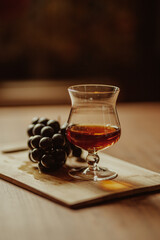 glass of cognac and grapes on a dark background