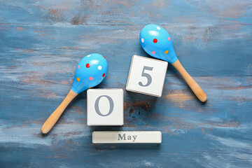 Mexican maracas and calendar with date 5 May (Cinco de Mayo) on wooden background