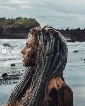 Woman with tattoo and dreadlocks on seashore