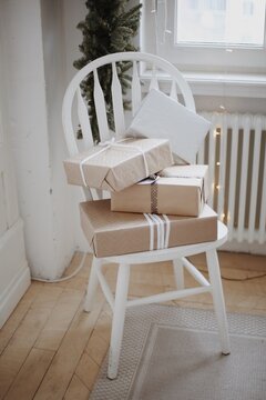Wrapped gift boxes on white chair near a Christmas decorated window indoor