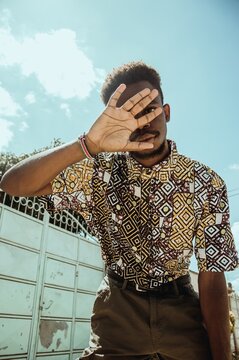 Worm view of man wearing shirt with square pattern hiding his face with his hand