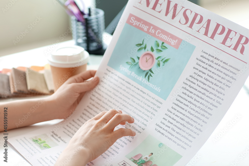 Poster Young woman reading newspaper at home, closeup