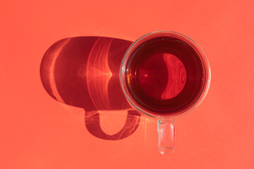 a mug of tea with a hard shadow on an red background