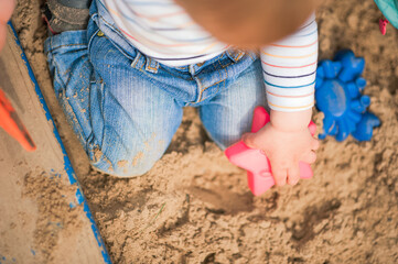 Child plays in sandbox with toys. Toddler hands with sand and copy space...