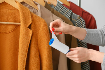 Woman cleaning clothes with lint roller, closeup