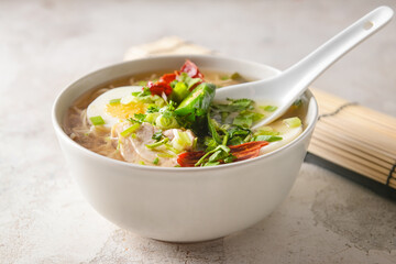 Tasty Chinese soup with chicken in bowl on light background