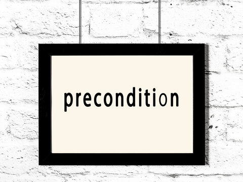 Black frame hanging on white brick wall with inscription precondition
