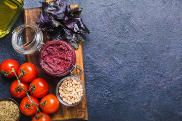 Composition with jar of tasty pesto sauce and ingredients on dark background