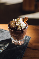 hot drinking chocolate in cafe glass with whipped cream, cinnamon, chocolate drizzle sauce 