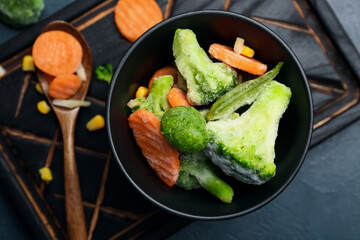 Composition with bowl of frozen vegetables on dark background, closeup