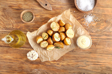Parchment with baked potatoes and rosemary on wooden background