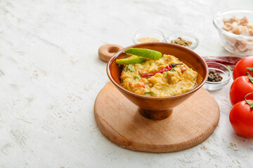 Bowl of tasty chicken curry on light background