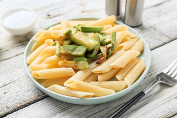 Plate of tasty pasta with zucchini on light wooden background