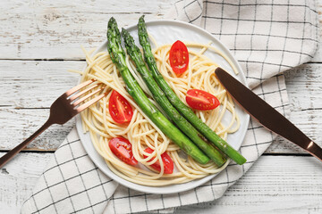 Plate of tasty pasta with vegetables on light wooden background