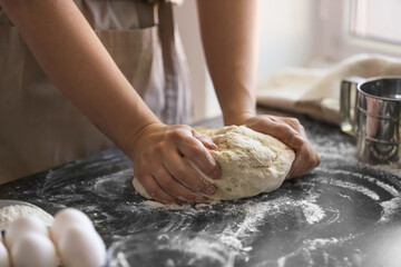 Obraz na płótnie Canvas Female chef preparing dough on kitchen table, closeup