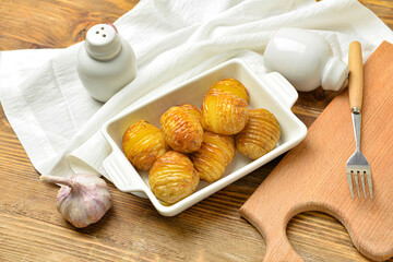 Dish with tasty baked potato on wooden background