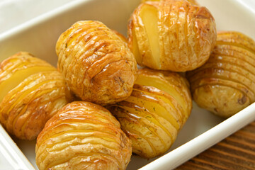 Dish with tasty baked potato on wooden background