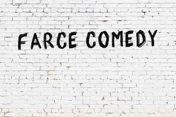 Inscription farce comedy painted on white brick wall