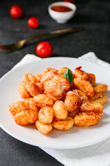 Delicious gnocchi with tomato sauce in plate on dark table, closeup