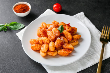 Delicious gnocchi with tomato sauce in plate on dark table