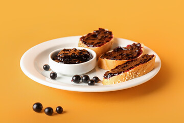 Toasts with black currant jam on color background
