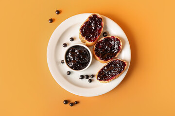 Toasts with black currant jam on color background