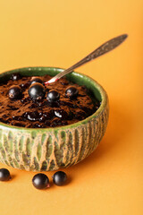 Bowl with black currant jam on color background