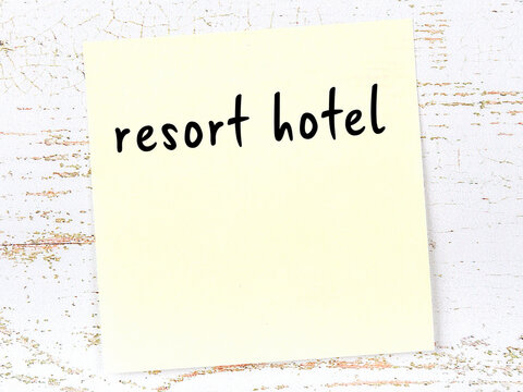 Yellow sheet of paper with word resort hotel. Reminder concept